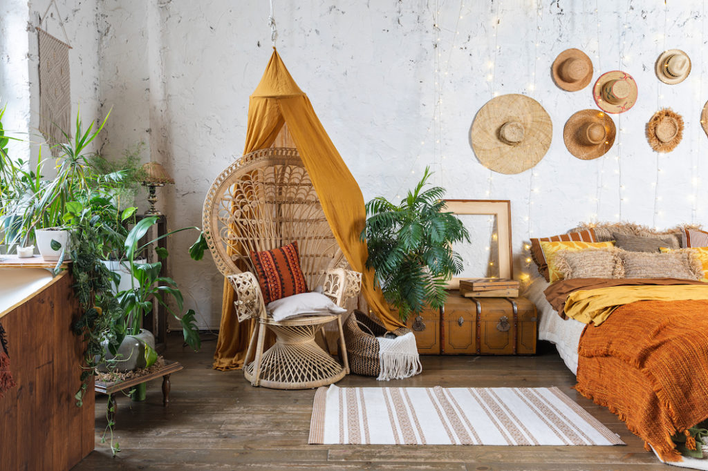 Wicker peacock chair in orange, vintage bohemian bedroom.