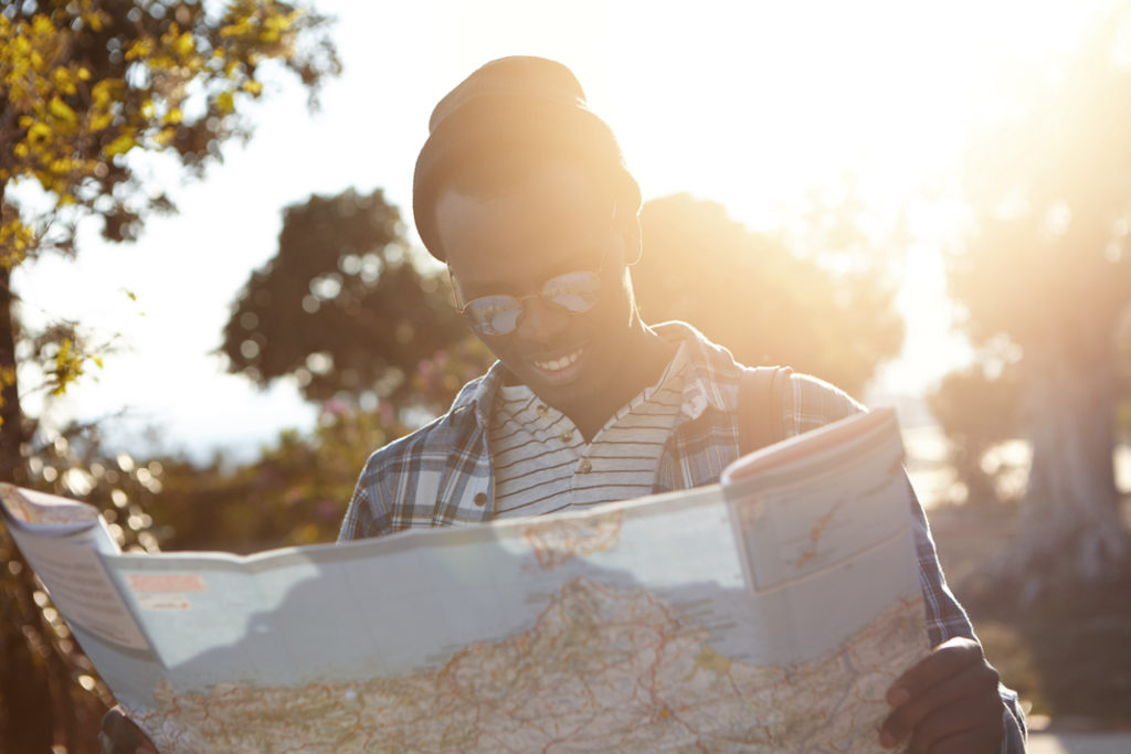Black man smiling and looking at a map. 