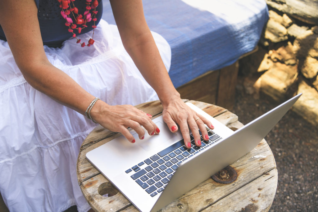 Woman working from laptop in rural setting. 